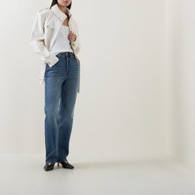 Model wearing Aje Mossan Utility Cropped Jacket in ivory with gold-toned hardware and epaulettes, styled with mid-blue straight-leg jeans and black