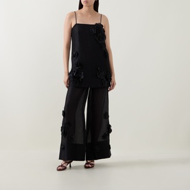 Model wearing Aje black floral appliqu&eacute; cami top, styled with matching wide-leg sheer trousers and strappy heeled sandals.