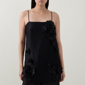 Model wearing Aje black linen-blend cami top with 3D floral appliqu&eacute; detail, styled with black wide-leg trousers