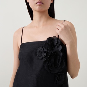 Model wearing Aje black linen-blend cami top with 3D floral appliqu&eacute; detail at bust, thin spaghetti straps
