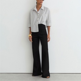 Model wearing Reiss white shirt with black flared trousers and gold cuff bracelet