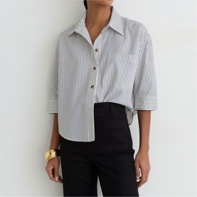 Model wearing Reiss white stripe shirt with black trousers, styled with a gold cuff bracelet