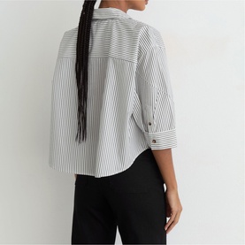 Model wearing Reiss white stripe cropped shirt, back view, with rolled sleeves and black trousers