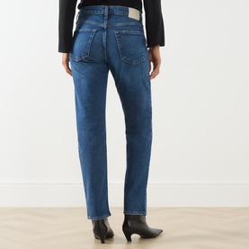 Model wearing Citizens of Humanity slim jeans in cruise blue denim, rear view, styled with black cropped top and ankle boots.