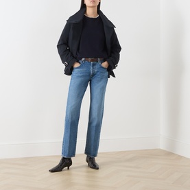Model wearing Citizens of Humanity straight jeans in pastis, styled with a dark jacket and black heeled ankle boots.