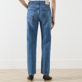 Model wearing Citizens of Humanity straight jeans in pastis, rear view showing five-pocket design and contrast stitching in mid-blue denim.
