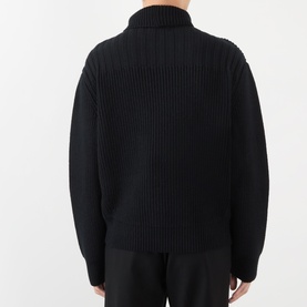 Model wearing Dries Van Noten black wool cardigan, back view, showing ribbed texture and turtleneck collar, paired with black trousers.