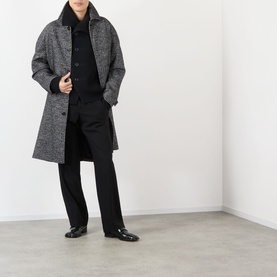 Model wearing Dries Van Noten black wool cardigan, styled with grey herringbone overcoat and black tailored trousers.