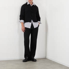 Model wearing Dries Van Noten Mora Brushed Knitted Cardigan in black with polo collar, styled over a striped shirt with black trousers.