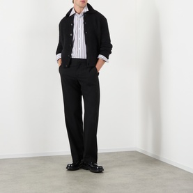 Model wearing Dries Van Noten Mora Brushed Knitted Cardigan in black with polo collar, styled with striped shirt and tailored trousers.
