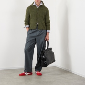 Model wearing Dries Van Noten Mora Brushed Knitted Cardigan in Forest Green with grey trousers, styled with red loafers and black tote bag.