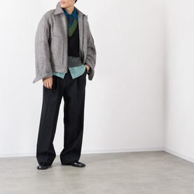 Model wearing Dries Van Noten black wool casual jacket, styled with blue polo, green scarf and black wide-leg trousers.