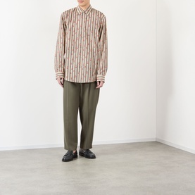 Model wearing Dries Van Noten Caper Printed Shirt in beige striped cotton with floral detail, styled with olive trousers and black loafers.