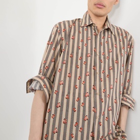 Model wearing Dries Van Noten Caper Printed Shirt in beige with vertical stripes and red floral print, point collar, long sleeves.