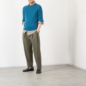 Model wearing Dries Van Noten Caper Printed Shirt in beige stripe, layered under teal knit, with olive tapered trousers and dark loafers.
