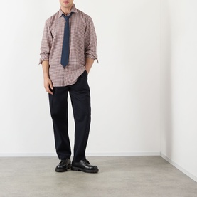 Model wearing Dries Van Noten red gingham cotton casual shirt with navy tie, black trousers and black chunky leather shoes.