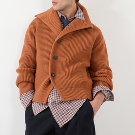 Model wearing Dries Van Noten red cotton casual shirt, layered under a tan ribbed knit cardigan with dark trousers.