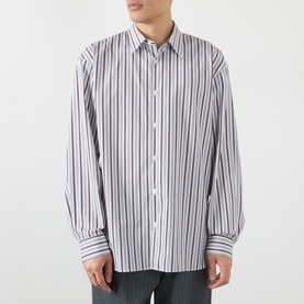 Model wearing Dries Van Noten Croom Striped Shirt in white cotton with multicolour stripes, point collar, dropped shoulders, and buttoned cuffs.