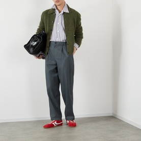 Model wearing Dries Van Noten Croom Striped Shirt in white cotton with olive cardigan, grey trousers and red loafers.