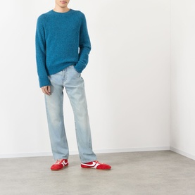 Model wearing Dries Van Noten Raf blue alpaca wool crew neck jumper, styled with light wash jeans and red trainers.