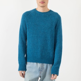 Model wearing Dries Van Noten Raf blue alpaca wool crew neck jumper, styled with light wash jeans.