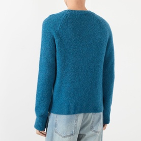 Model wearing Dries Van Noten Raf blue alpaca wool crew neck jumper, back view, styled with light wash jeans.