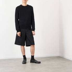 Model wearing Dries Van Noten black alpaca wool crew neck jumper, styled with wide-leg black shorts and black leather shoes.
