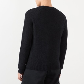 Model wearing Dries Van Noten black alpaca wool crew neck jumper, rear view showing textured knit and ribbed hem.