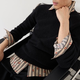 Model wearing Dries Van Noten black alpaca wool crew neck jumper, styled over a striped floral shirt.