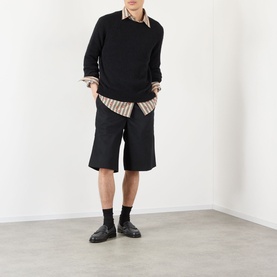 Model wearing Dries Van Noten black alpaca wool crew neck jumper with black shorts, striped shirt, black socks and loafers.