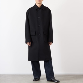 Model wearing Dries Van Noten Randale Single-Breasted Car Coat in black with flat collar, flap pockets, styled with dark wide-leg trousers.
