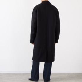 Model wearing Dries Van Noten Randale Single-Breasted Car Coat in black, longline silhouette with dropped shoulders, styled with navy trousers, back