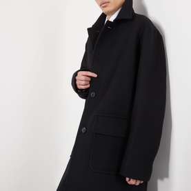 Model wearing Dries Van Noten Randale Single-Breasted Car Coat in black with flat collar, button fastening, and flap pockets