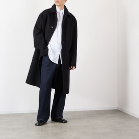 Model wearing Dries Van Noten Randale Single-Breasted Car Coat in black, styled with a white shirt, wide-leg jeans and black loafers.