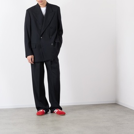 Model wearing Dries Van Noten black wool trousers with matching oversized blazer and red trainers.