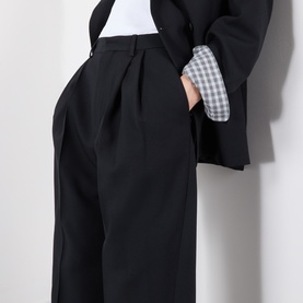 Model wearing Dries Van Noten black wide-leg wool trousers with pleated front, styled with a black blazer and gingham shirt.