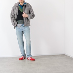 Model wearing Dries Van Noten black wool knitwear, styled with grey jacket, light blue jeans and red trainers.