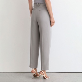 Model wearing Reiss grey wide-leg tailored trousers with belt detail, styled with white strappy heeled sandals, rear view.