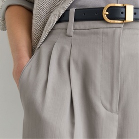 Model wearing Reiss grey wide-leg tailored trousers with front pleats, styled with a black leather belt with gold buckle.