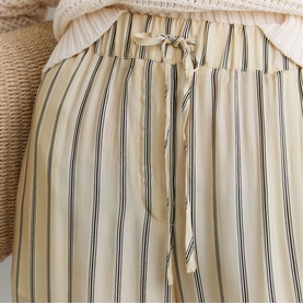 Reiss beige striped wide-leg trousers with drawstring waist, styled with a cream knit top. Button-front detail visible.