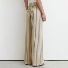Model wearing Reiss beige wide-leg striped trousers, rear view showing high waist and full-length hem with vertical stripe pattern.