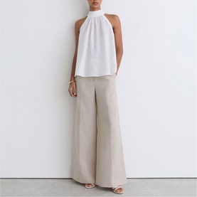 Model wearing Reiss white halterneck sleeveless top styled with wide-leg tailored trousers in stone