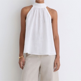 Model wearing Reiss white halterneck top with gathered neckline, styled with beige wide-leg trousers and gold bangle.