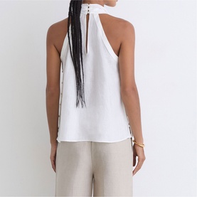 Model wearing Reiss white sleeveless halterneck top with keyhole back detail, styled with beige wide-leg trousers