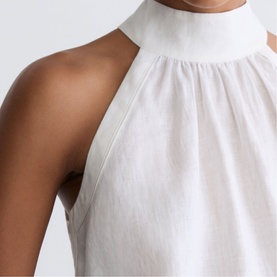 Model wearing Reiss white halterneck dress, close-up detail of high neck and sleeveless gathered bodice