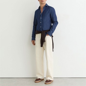 Model wearing Reiss dark blue wash shirt with cream trousers and brown loafers, brown jacket tied at waist