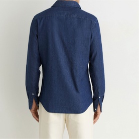 Model wearing Reiss dark blue wash denim shirt, back view, styled with cream trousers