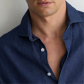 Model wearing Reiss dark blue wash denim shirt, open collar detail, close-up chest and neckline view