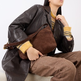 Model carrying Miu Miu Camoscio Small Shoulder Bag in Moro brown suede with tan leather strap, styled with brown leather jacket and striped knit