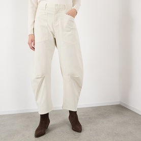 Model wearing Nili Lotan stone cotton trousers with relaxed fit and knee detailing, styled with dark brown ankle boots.